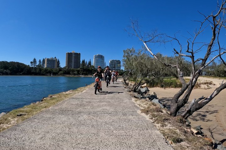 Family of four cycling on ecoTekkSC’s River to River e-Bike Tour along Mooloolaba Harbour northern rock wall