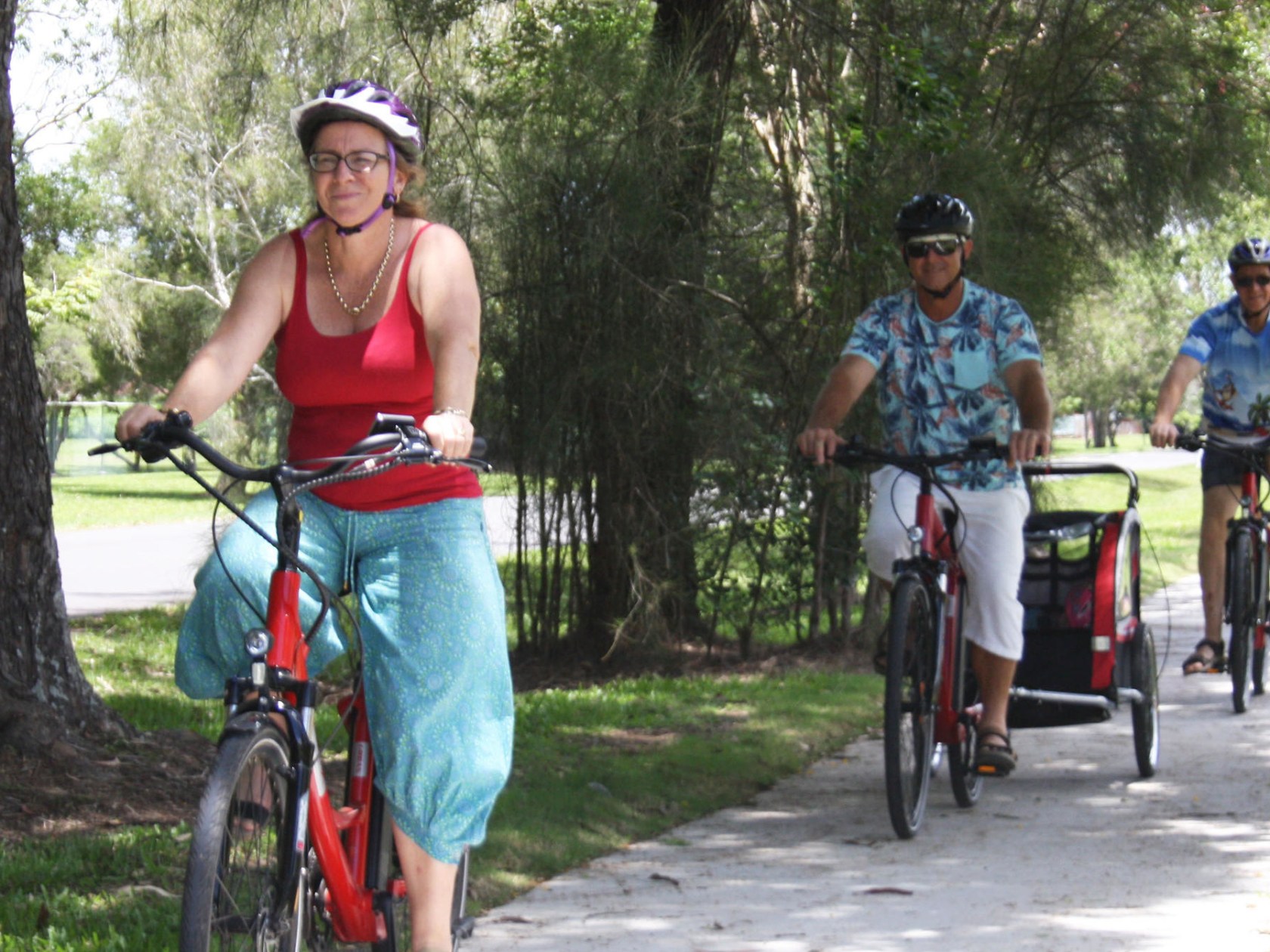 Grandparents and uncle riding EcoTekk Sunshine Coast e-bikes on Yandina pathways, with grandkids in a child trailer towed by granddad after a visit to the Ginger Factory.