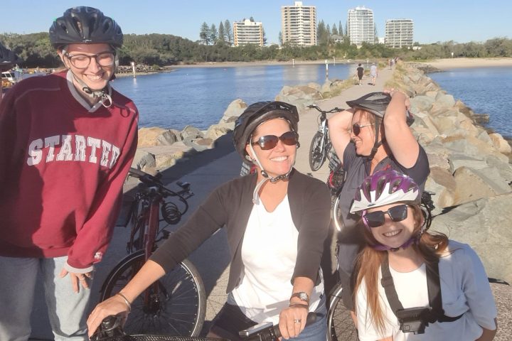 Five friends enjoying a girls' day out on ecoTekkSC hired e-bikes at Mooloolaba Spit Rock Wall, smiling and creating lifelong memories.