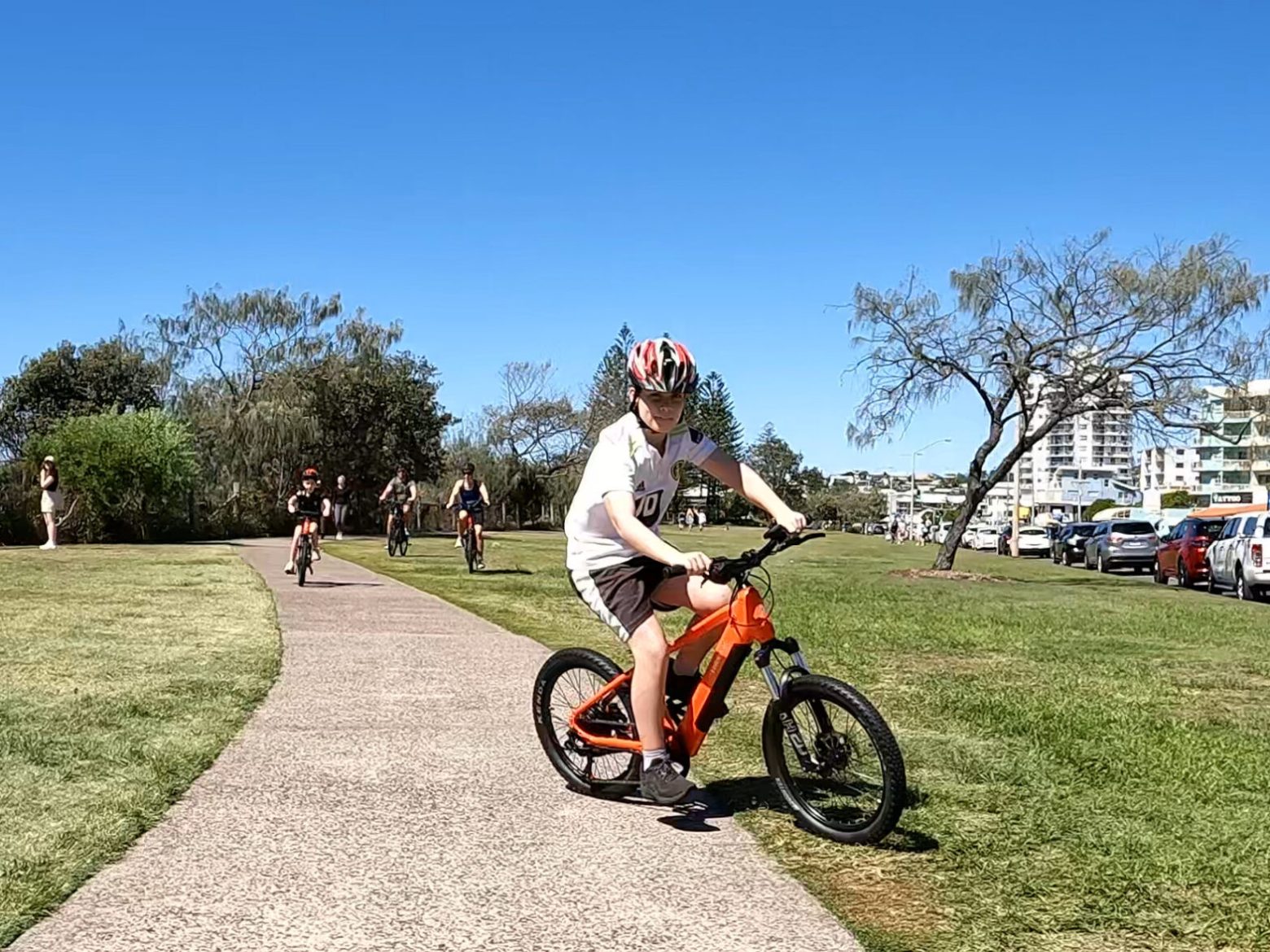Family of five riding ecoTekkSC hired e-bikes along the coastal pathway at Alexandra Headland. Youths aged 9 and 11 on 20