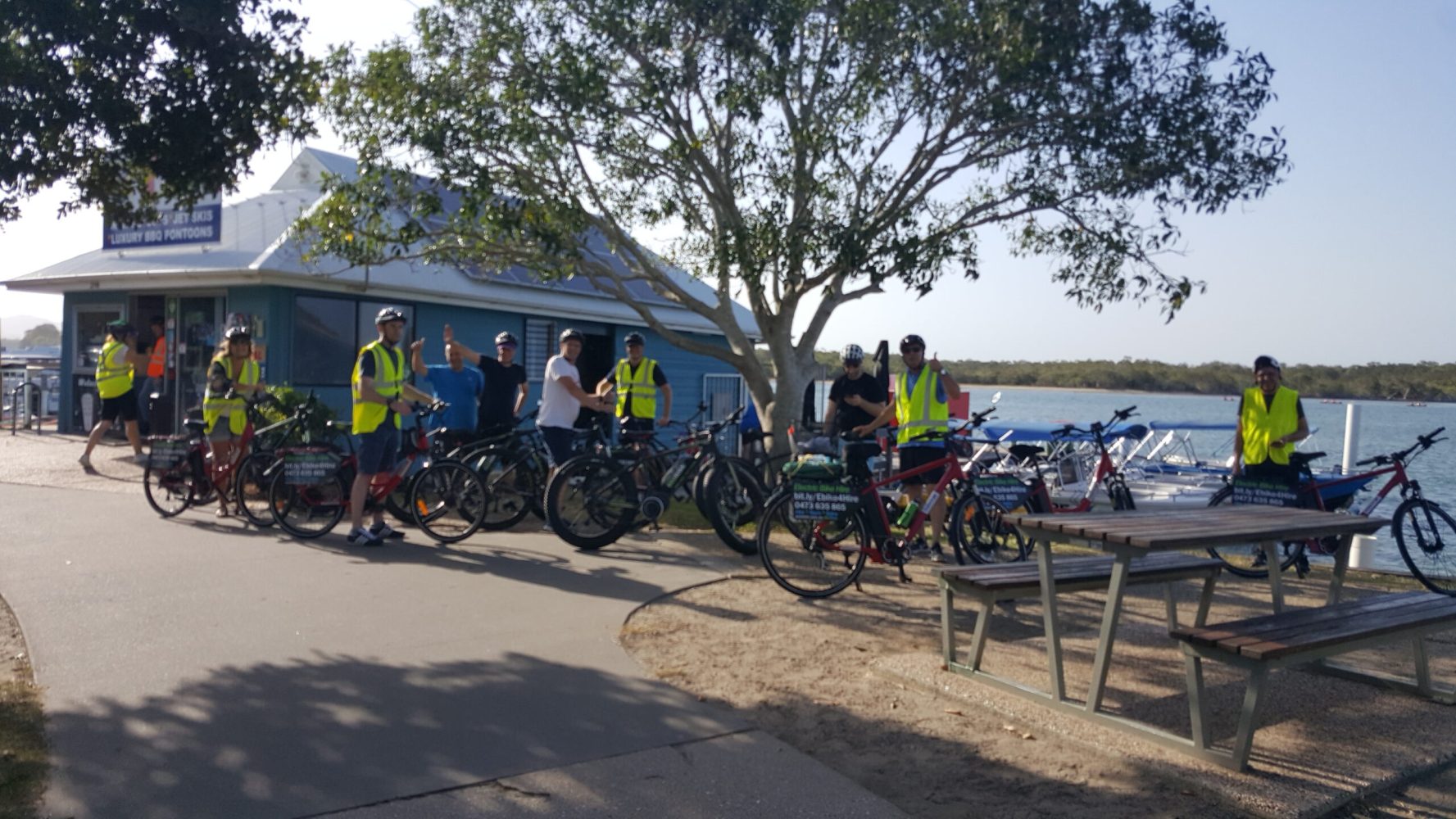 C-suite group on an EcoTekk e-bike corporate tour of the Noosa Biosphere, starting at Sofitel Noosa Pacific Resort, riding to Teewah Beach Access via the Noosa North Shore Ferries, and returning with a refreshment stop at STOP 5 Noosa Ferry.