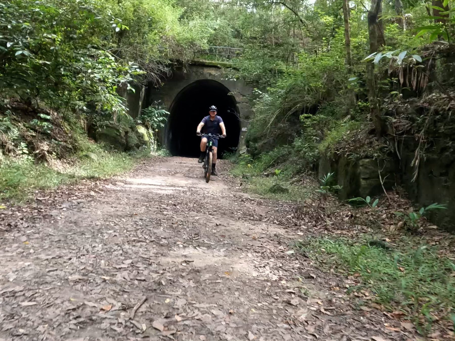 EcoTekkSC e-MTB rider emerges from Dularcha Railway Tunnel on tunnel track, Dularcha National Park.