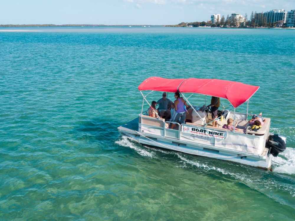 A group of people in a pontoon boat on Pumicestone Passage, enjoying a sunny day after riding e-bikes from their accommodation to Bill's Boat Hire on Golden Beach, Caloundra, Queensland.