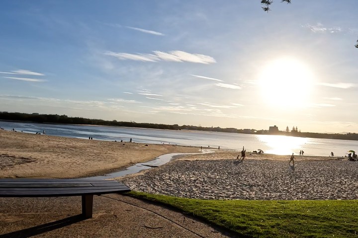 Sunset over Golden Beach on the Easy Peasy Rumba Caloundra e-Bike Tour, with sparkling waters of the Pumicestone Passage and the Glasshouse Mountains silhouetted in the distance.
