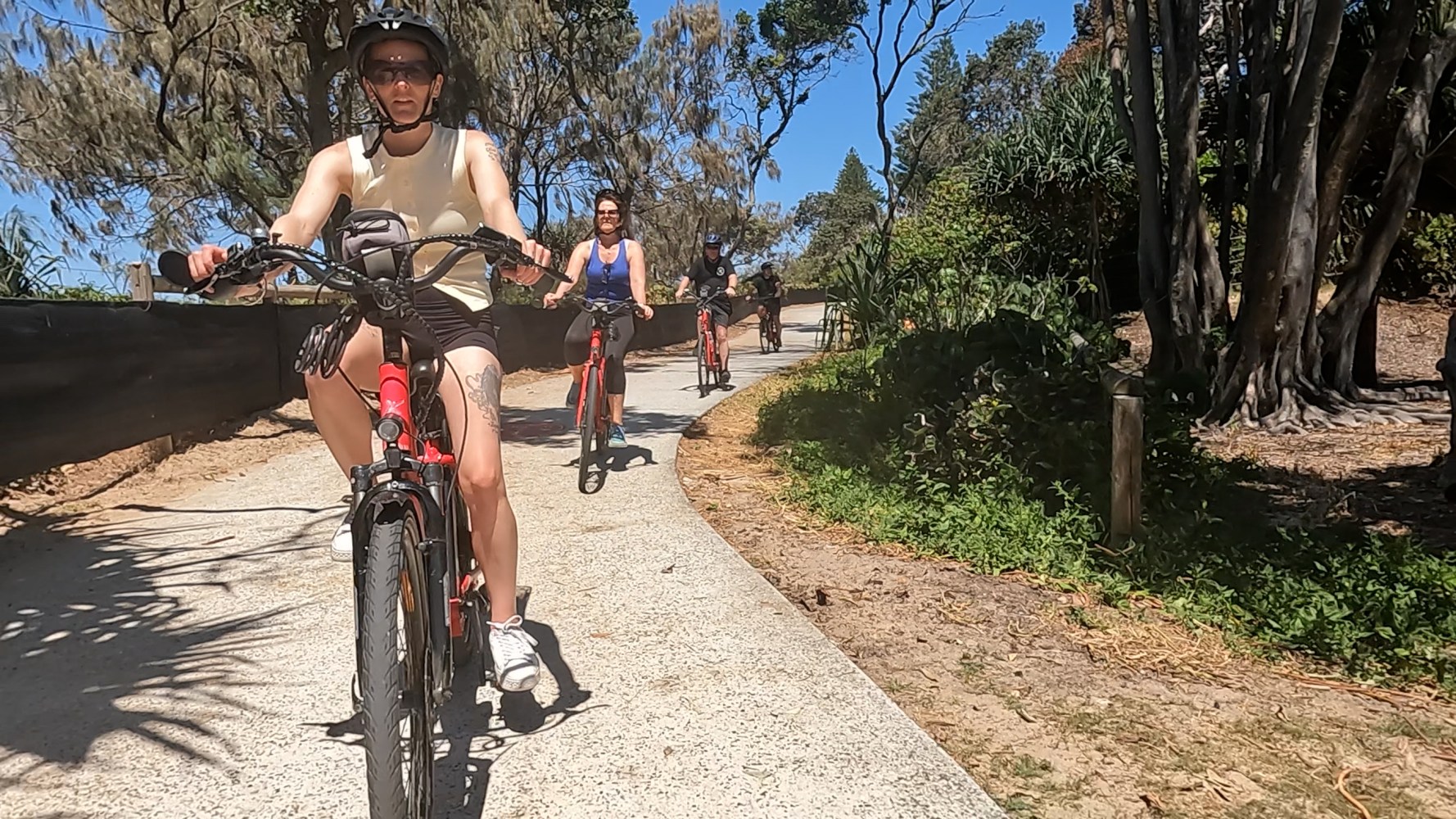 Four ecoTekkSC e-bike riders on the path near Dicky Beach with beach restoration underway
